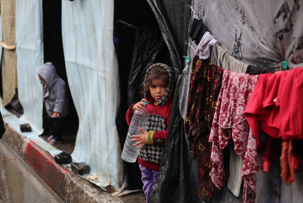 © UNICEF/Eyad El Baba A girl stands in front of her shelter in the city of Rafah.
