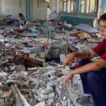 © UNRWA/Fadi Thabet غزہ کا ایک فلسطینی بچہ بمباری میں تباہ ہو جانے والے اپنے سکول کے ملبے پر پریشان بیٹھا ہے۔