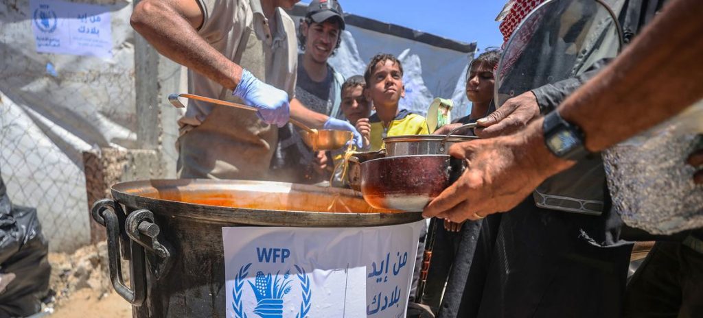 © WFP/Ali Jadallah غزہ میں عالمی پروگرام برائے خوراک کے تحت کام کرنے والے ایک کچن میں کھانا تقسیم کیا جا رہا ہے۔