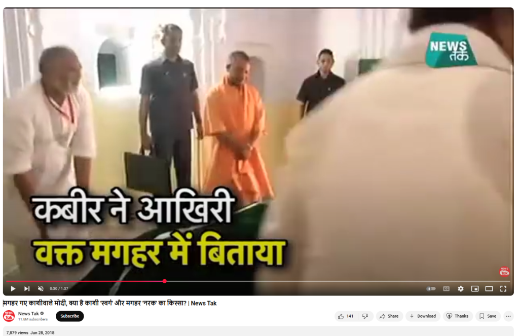 "Screenshot from a YouTube video uploaded by News Tak, titled 'मगहर गए प्रधानमंत्री मोदी, क्या है काशी स्वर्ग और मगहर नरक का किस्सा?' (Prime Minister Modi visits Maghar, what is the story of Kashi as heaven and Maghar as hell?). The video has over 7,800 views and was published on June 28, 2018. The scene shows Indian Chief Minister Yogi Adityanath dressed in saffron robes, standing with folded hands inside a white-arched spiritual or historical monument, accompanied by security personnel and local attendees. The Hindi headline overlaid on the video frame reads: 'कबीर ने आखिरी वक्त मगहर में बिताया' (Kabir spent his final moments in Maghar). The logo of News Tak is visible in the top right corner. This image relates to a documentary-style news segment discussing the legacy of 15th-century poet-saint Kabir, his association with the town of Maghar in Uttar Pradesh, and the spiritual significance of his last days spent there.